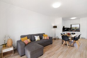 Un salon moderne avec un canapé gris, une table à manger en bois et des chaises noires.