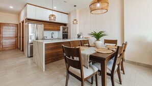 Une cuisine moderne dotée d’un îlot central, de meubles en bois, d’appareils électroménagers en acier inoxydable et d’un coin repas avec une table et des chaises.