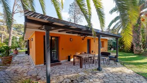 A modern building with a stone patio, outdoor seating, and palm trees. - Villa 'Dependance' with Shared Pool, Wi-Fi and Air Conditioning (Lecce)