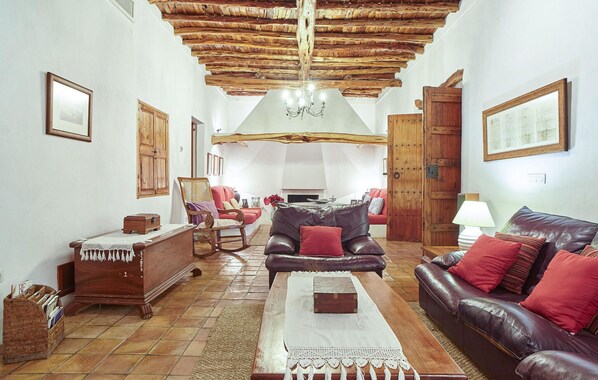 A cozy living room with a wooden ceiling, a fireplace, a leather sofa, and a wooden coffee table.