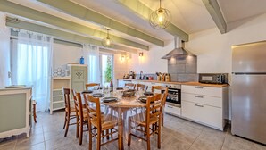 Una cocina moderna con una mesa de comedor preparada para seis personas, un refrigerador de acero inoxidable y un horno empotrado.