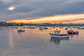 Un puerto con barcos, agua tranquila y un pueblo lejano.