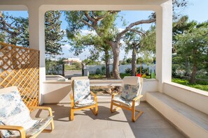 Een overdekt terras met twee stoelen en een houten schutting.