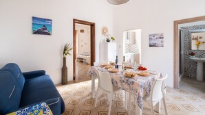 A dining area with a table set for four, a blue sofa, and a kitchen area with a sink and mirror.