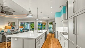 Una cocina moderna con una isla grande, electrodomésticos de acero inoxidable y vistas al área exterior.