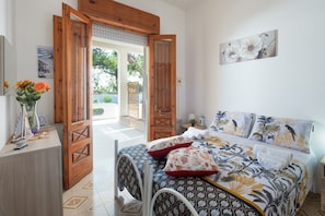 Una camera da letto con un letto, una porta in legno, un tavolino con un vaso e un quadro appeso al muro.