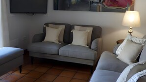 A living room with a grey sofa, a television mounted on the wall, and a lamp on a side table. - Country House 'Fuentebuena' with Mountain View, Private Terrace and Wi-Fi (Matabuena)