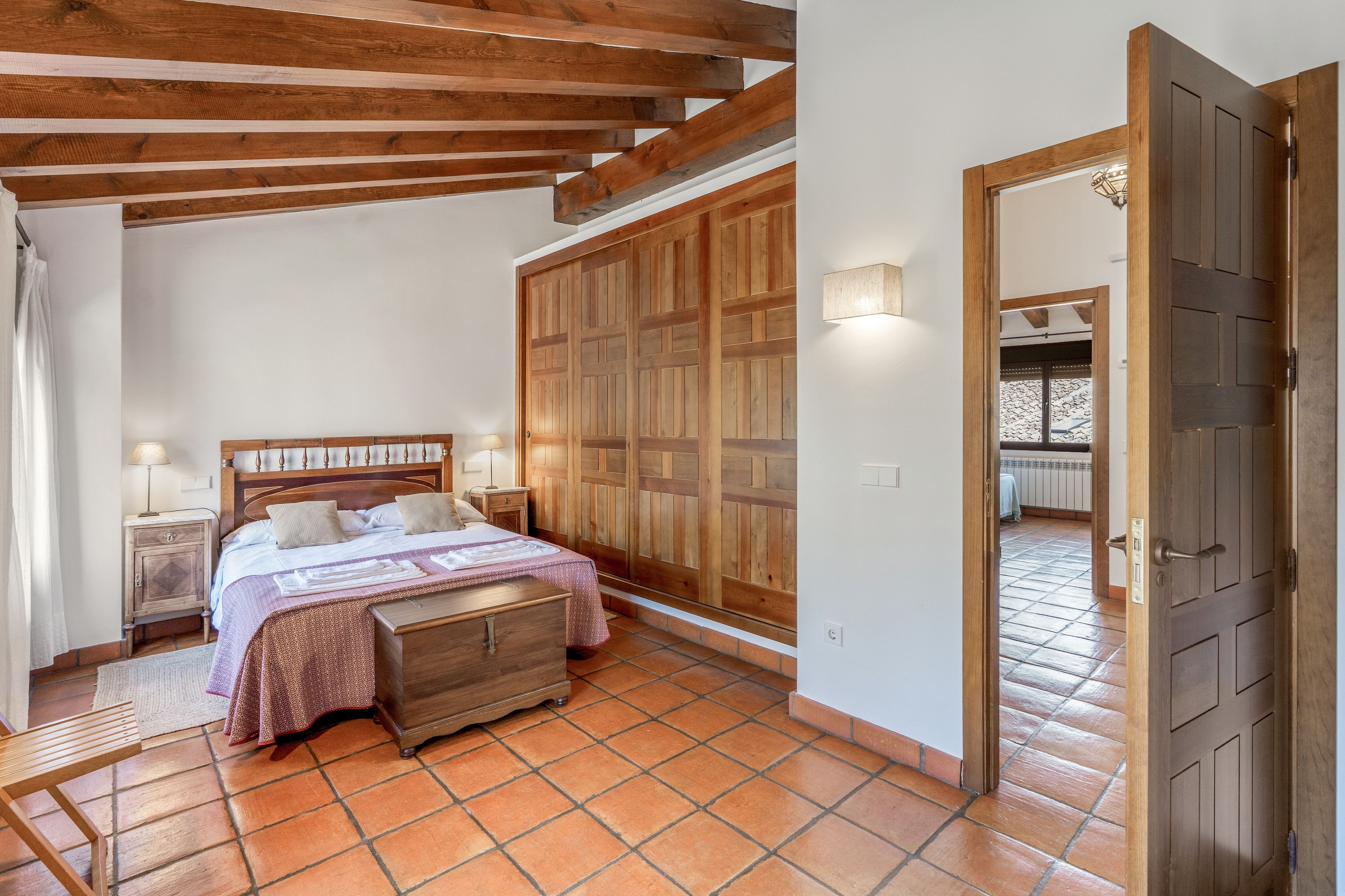 Une chambre à coucher avec un lit en bois, une table de chevet, une armoire et un sol carrelé.