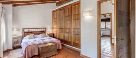 A bedroom with a wooden bed, a nightstand, a wardrobe, and a tiled floor.