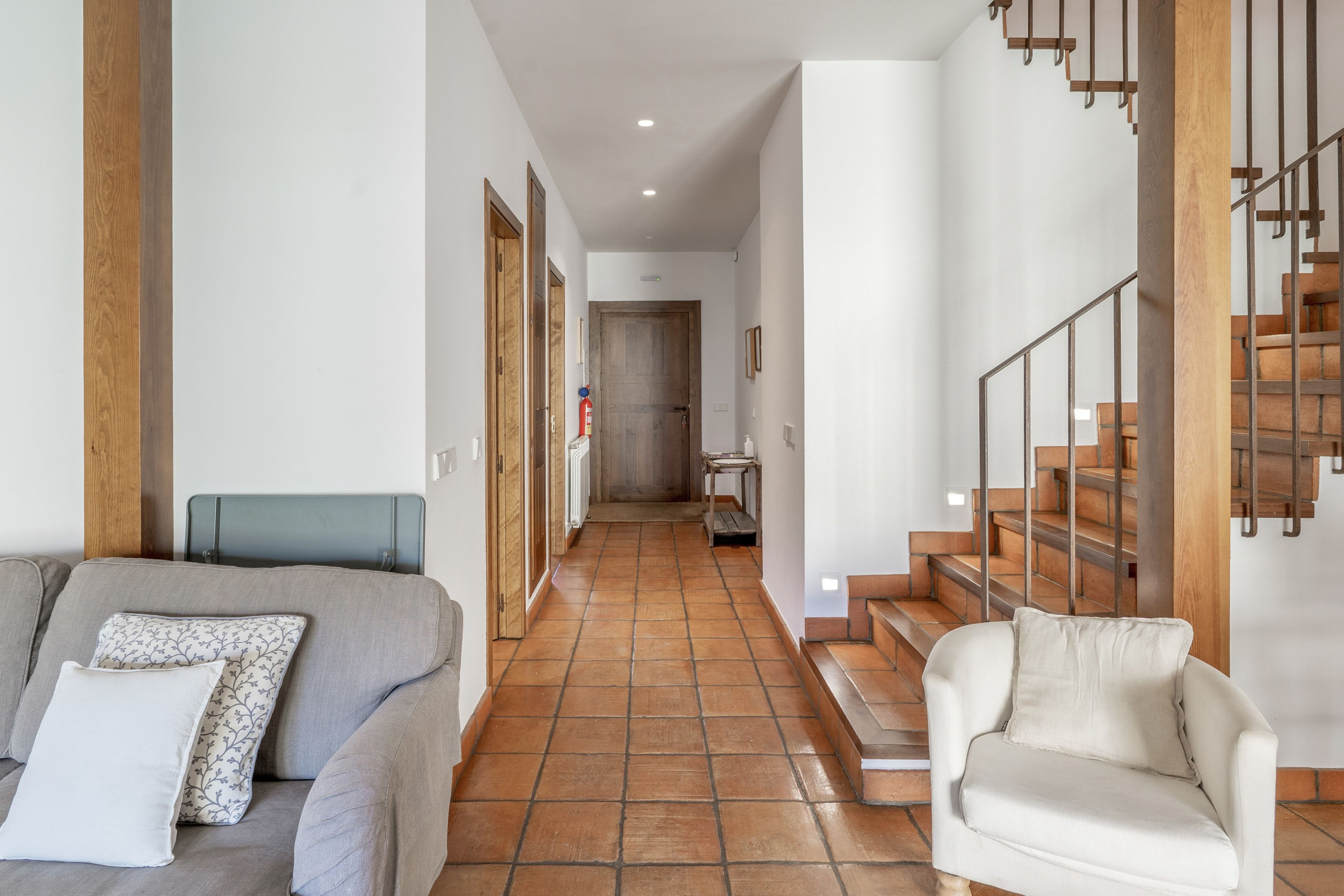 Un pasillo con un sofá, una silla y una escalera.