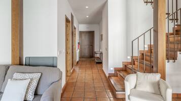 Un pasillo con un sofá, una silla y una escalera.