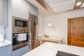 Cozinha moderna com eletrodomésticos de aço inoxidável, micro-ondas e geladeira.