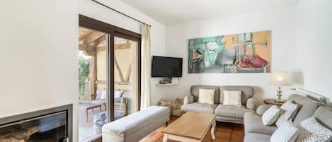 Una sala de estar con chimenea, un conjunto de sofás, una mesa de centro y un televisor.