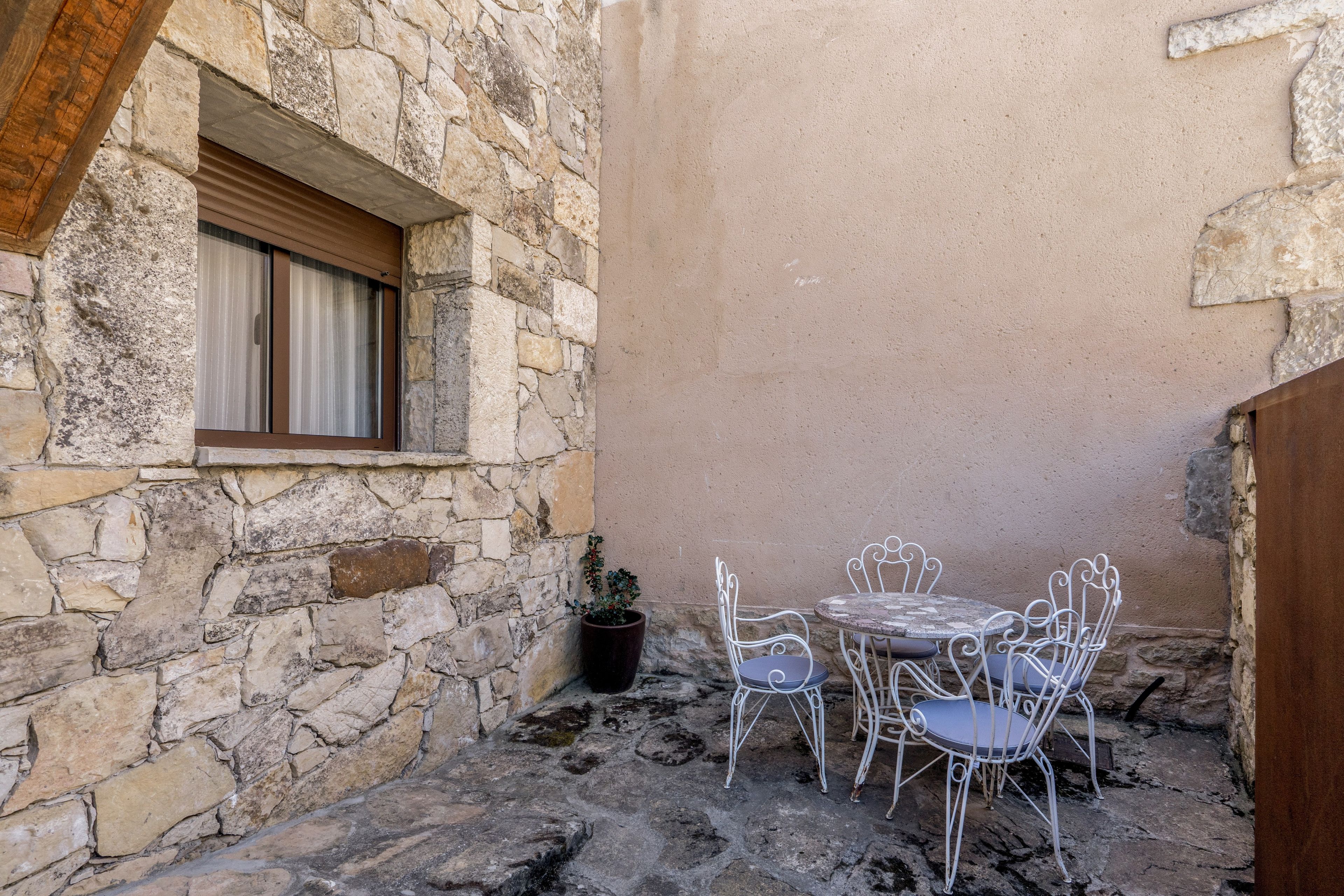 A stone building with a window and a table with chairs.
