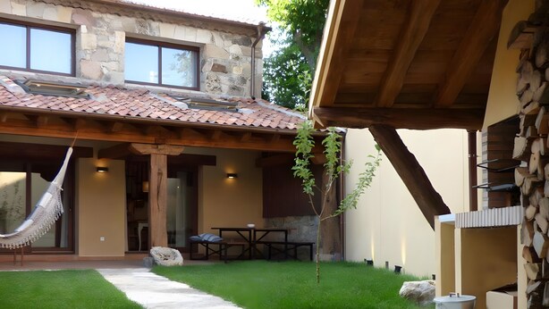 A stone building with a tiled roof, a hammock, a small lawn, and a concrete patio. - Country House 'Fuentebuena' with Mountain View, Private Terrace and Wi-Fi (Matabuena)