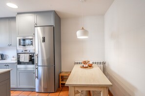 A modern kitchen with stainless steel appliances, a wooden table with bread, and a hanging light fixture. - Country House 'Fuentebuena' with Mountain View, Private Terrace and Wi-Fi (Matabuena)
