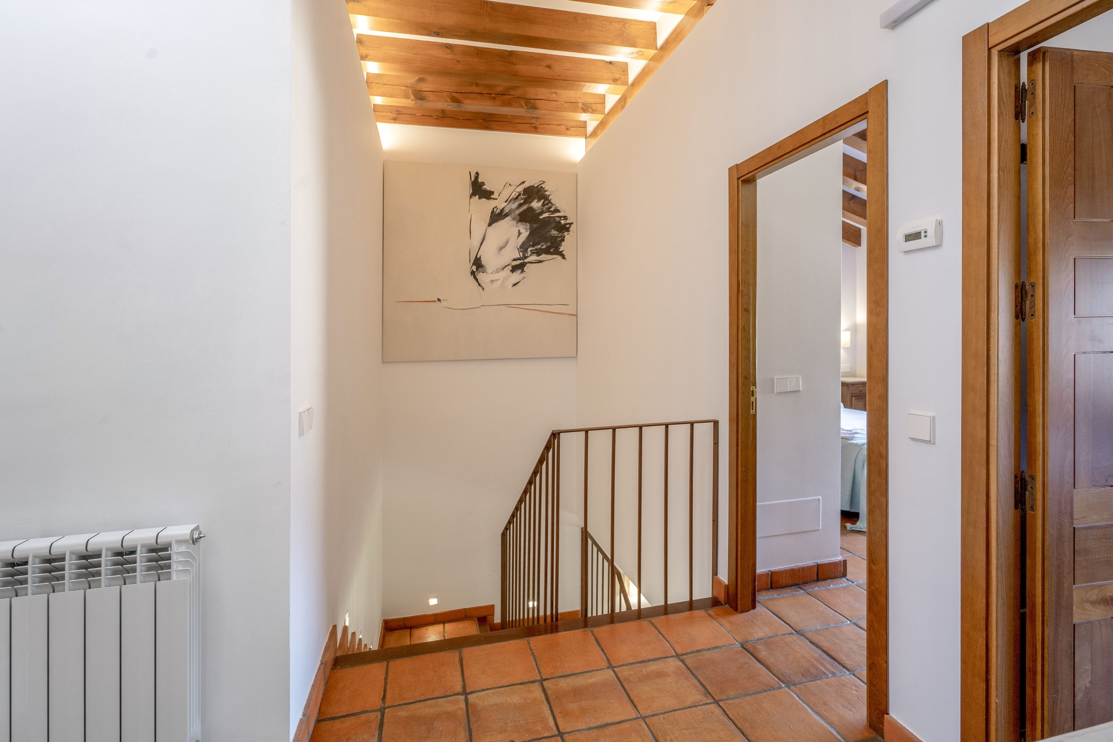 Escada com corrimão de madeira e obra de arte na parede.