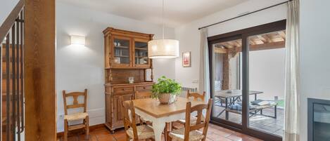 Un comedor con una mesa y sillas de madera, un armario y una lámpara colgante.