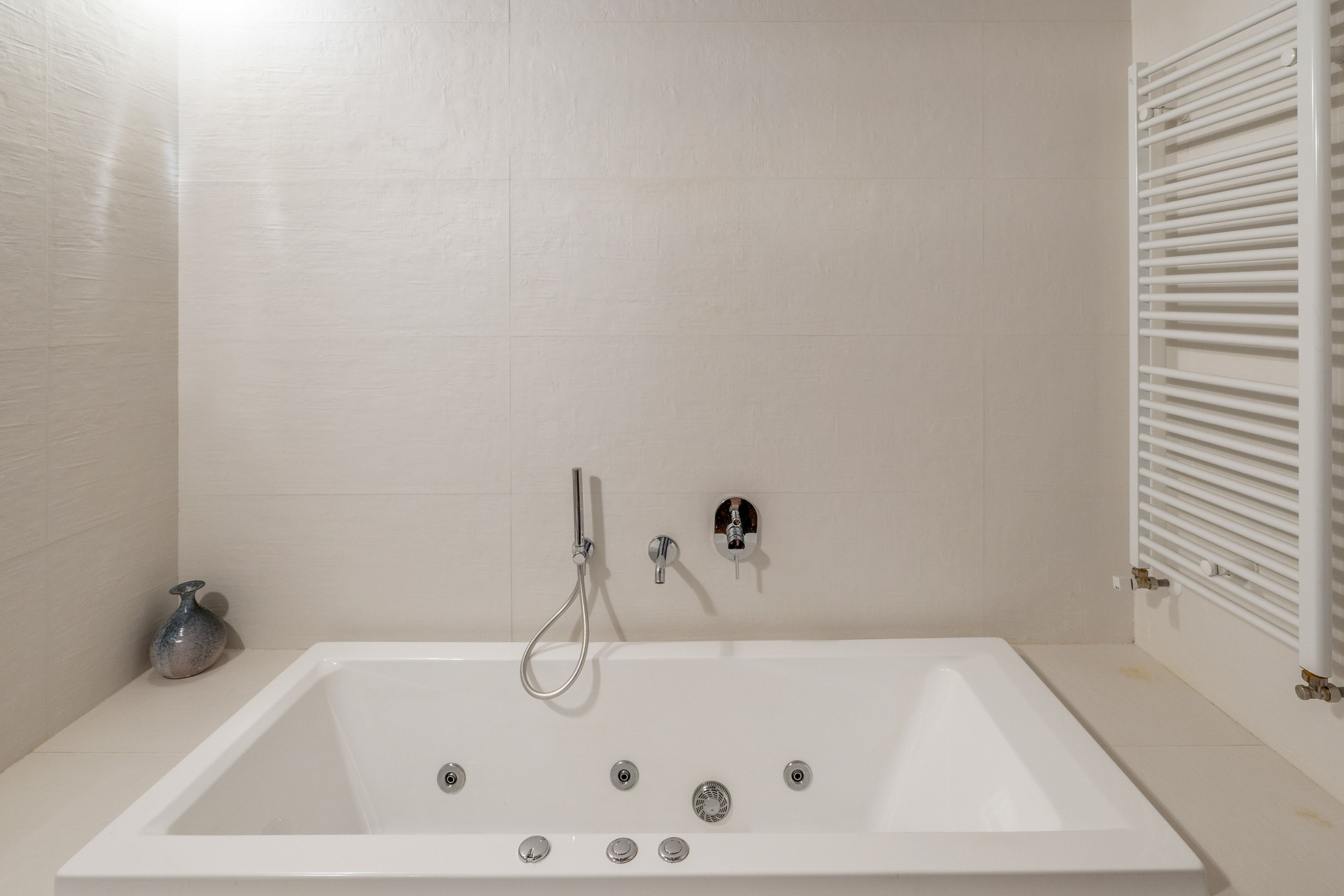 Un baño moderno con una bañera independiente, un cabezal de ducha manual y un grifo empotrado.
