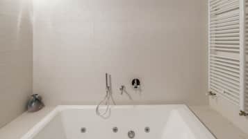 Un baño moderno con una bañera independiente, un cabezal de ducha manual y un grifo empotrado.