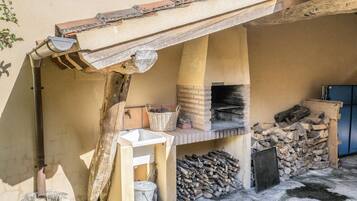 Una cocina rústica al aire libre con un horno de ladrillo, un lavamanos y un banco de madera.