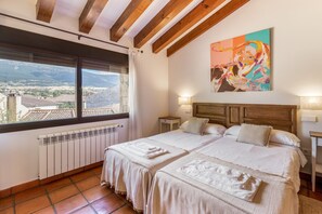 Une chambre d’hôtel avec deux lits, une grande fenêtre donnant sur un beau paysage, un radiateur et un tableau accroché au mur.