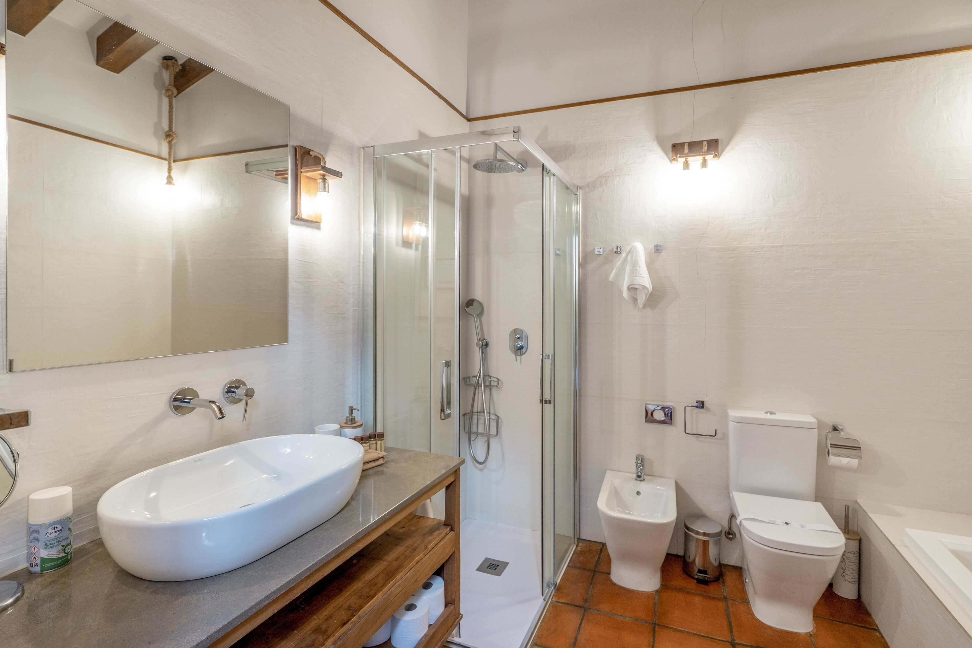 Ein modernes Badezimmer mit einem großen weißen Waschbecken, einer Duschkabine aus Glas, einer Toilette und einem Bidet.