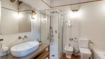 Ein modernes Badezimmer mit einem großen weißen Waschbecken, einer Duschkabine aus Glas, einer Toilette und einem Bidet.