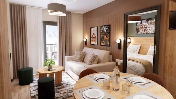 Een moderne hotelkamer met een bank, een eettafel voor twee personen en een bed met een houten hoofdeinde.