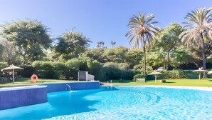 A swimming pool with clear blue water, surrounded by lush greenery and palm trees. - Apartment 'Ola De Mar' with Shared Pool, Wi-Fi and Air Conditioning (Estepona)