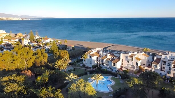 A coastal residential area with modern buildings, a swimming pool, and a beach. - Apartment 'Ola De Mar' with Shared Pool, Wi-Fi and Air Conditioning (Estepona)