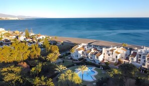 A coastal residential area with modern buildings, a swimming pool, and a beach. - Apartment 'Ola De Mar' with Shared Pool, Wi-Fi and Air Conditioning (Estepona)