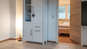 Una stanza con un armadio bianco, un comodino e un letto con copripiumino fantasia.