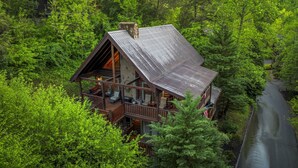 Eine Blockhütte mit Balkon, umgeben von dichtem Wald und einem Fluss.