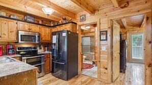 Eine Holzhütte mit einer Küche, inklusive Kühlschrank, Herd, Mikrowelle und Kaffeemaschine.