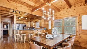 L’intérieur d’un chalet en bois comprend un coin repas, une cuisine et de grandes fenêtres.