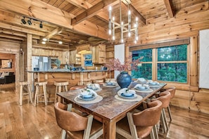 Un intérieur en bois avec une table à manger dressée pour six personnes, entourée de chaises en bois.
