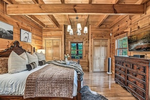 Une chambre dans une cabane en rondins, avec un lit, une commode et des œuvres d’art accrochées aux murs.