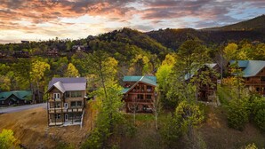 Un complexe touristique composé de plusieurs chalets en rondins, entouré de collines boisées et offrant une vue sur un ciel dégagé.