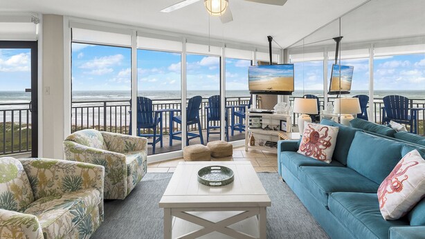 A spacious balcony with a view of the ocean, furnished with blue chairs and a white table. - Sea Gull #503L: Beachfront 2 Bedroom 2 Bathroom With Spectacular Views and 24 Hour Management (Port Aransas)