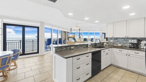 A modern kitchen with a large island, white cabinetry, and a view of the ocean. - Sea Gull #503L: Beachfront 2 Bedroom 2 Bathroom With Spectacular Views and 24 Hour Management (Port Aransas)