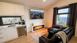 Una sala de estar moderna con chimenea, un sofá, una cafetera y un televisor.
