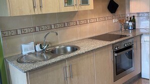 A modern kitchen with wooden cabinets, a stainless steel sink, and a built-in oven.