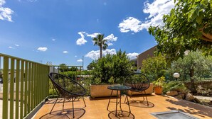 Une terrasse extérieure avec deux chaises et une table, entourée de verdure et sous un ciel dégagé.