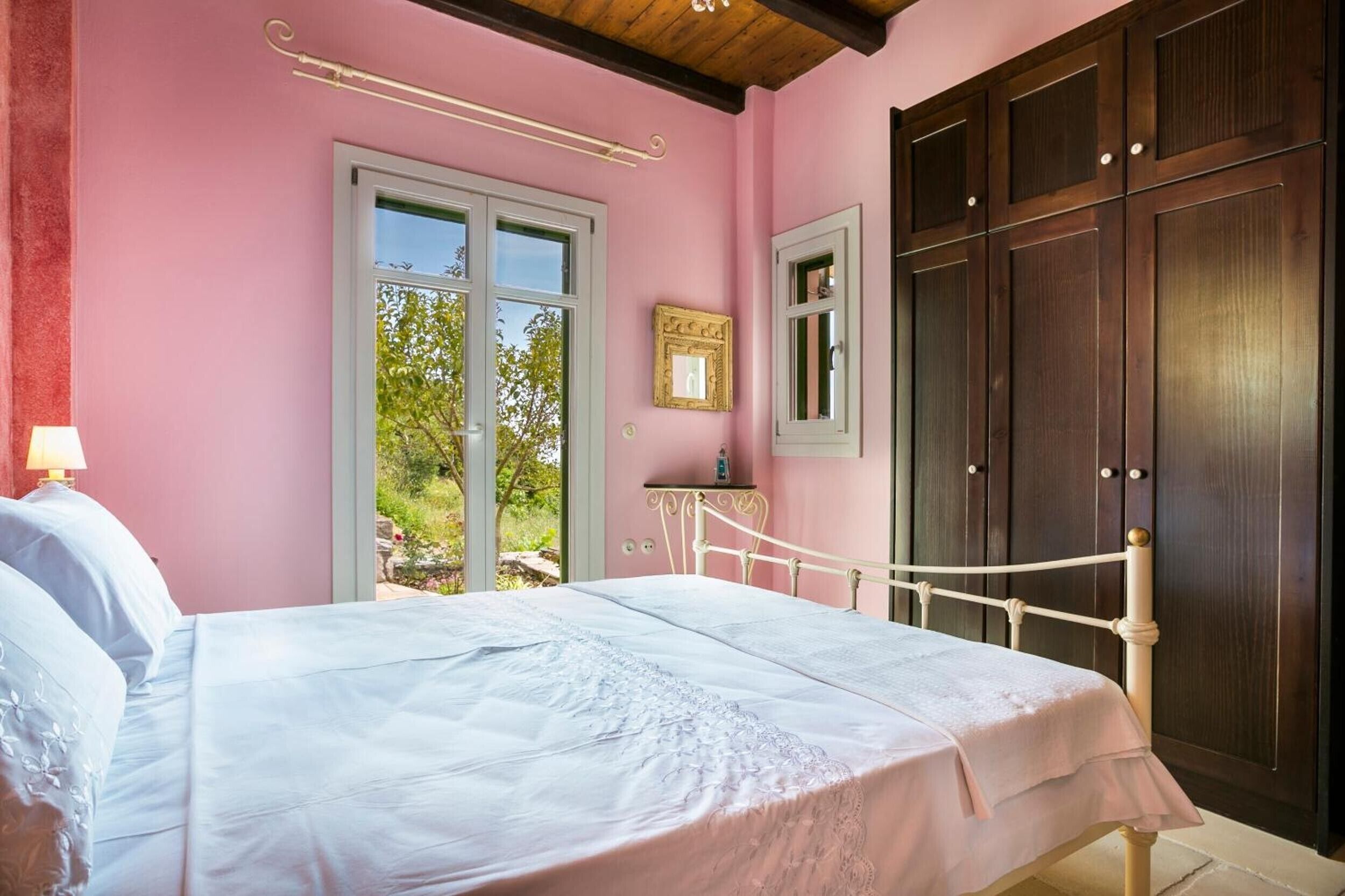 Un dormitorio con cama, ventana, armario y mesita de noche.