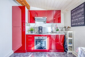 Eine moderne Küche mit roten Schränken, einem eingebauten Backofen und einer Kaffeemaschine.