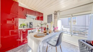 A modern kitchen with red cabinets, a dining table set for two, and a view of the outside.