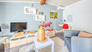 A modern living room with a flat-screen TV, a woven vase, and a red chair.