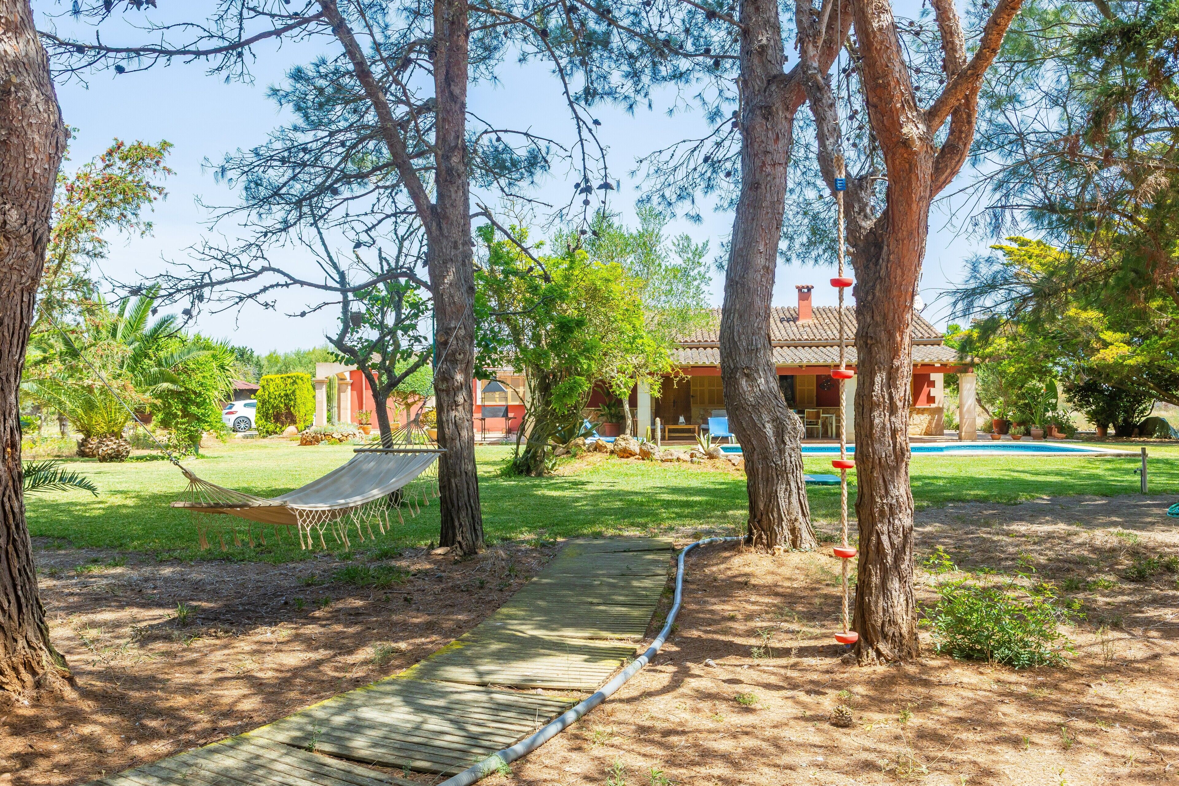A residential property with a swimming pool, a hammock, and a wooden deck.