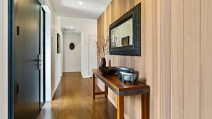 A hallway with a wooden panel wall, a mirror, and a table with a bowl and vase.